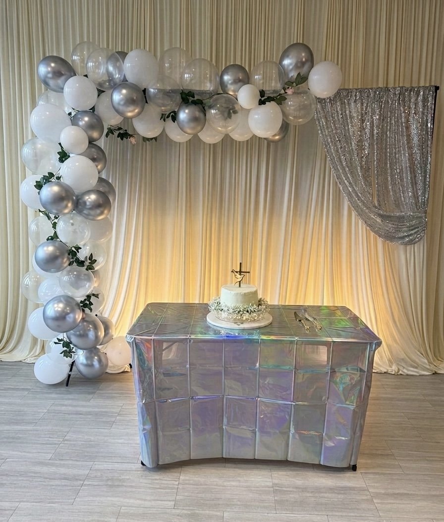 Silver balloon arch with iridescent cake table and draped backdrop